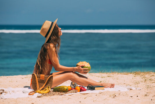Women sitting on beach with coconut basking in sun
