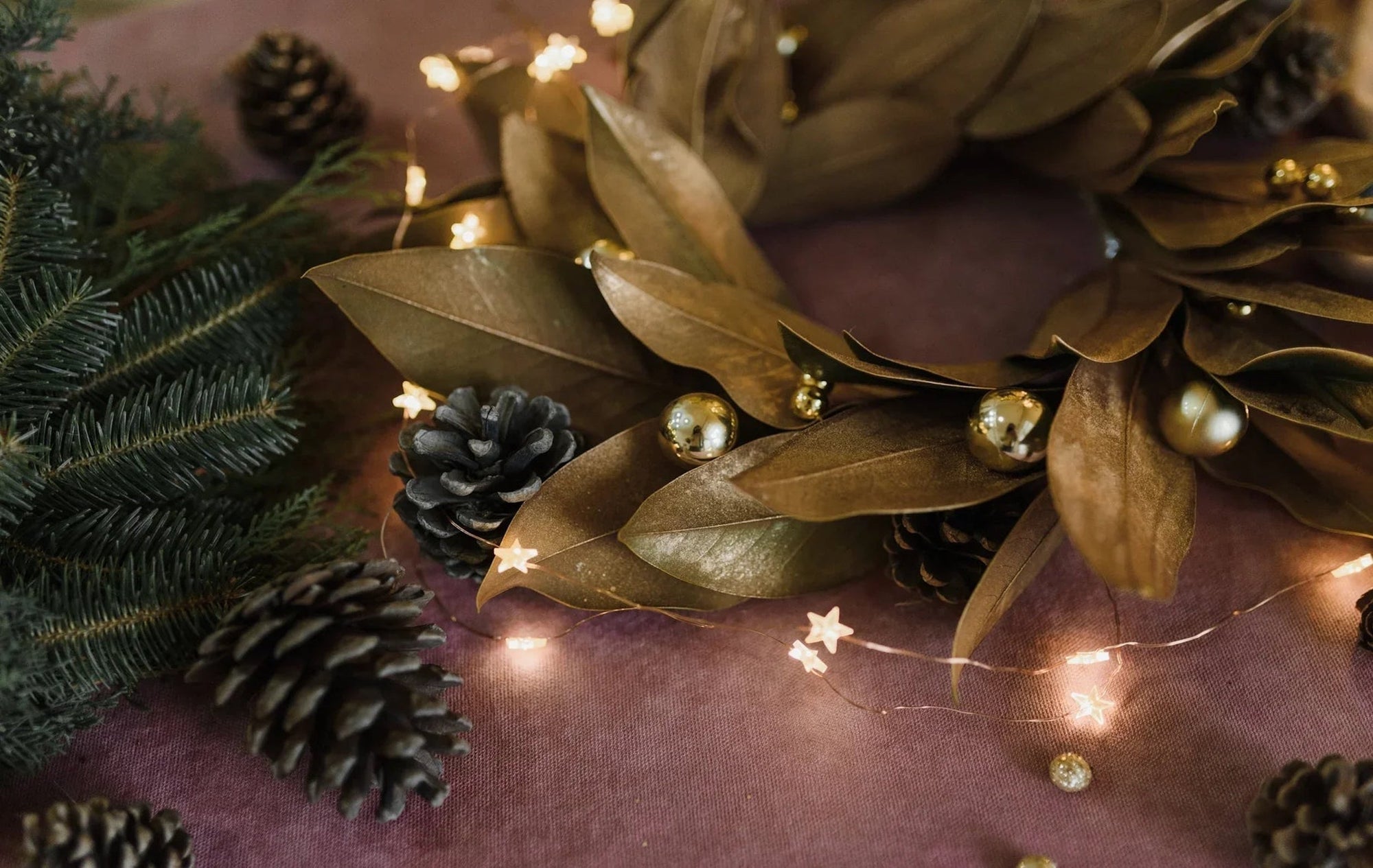 golden wreath with pine leaves, pine cones, and fairy lights